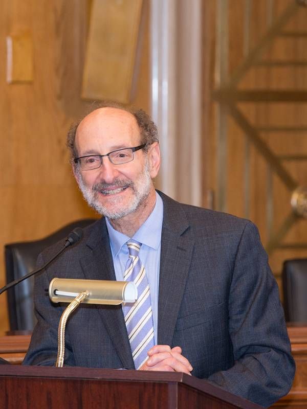 Dr. Steven Albert speaking at a podium, COVID-19 vaccine