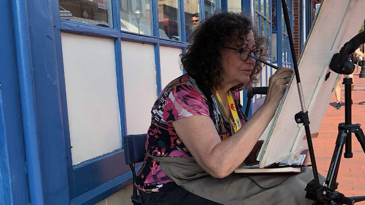 Woman painting on the street, Medicare recipients