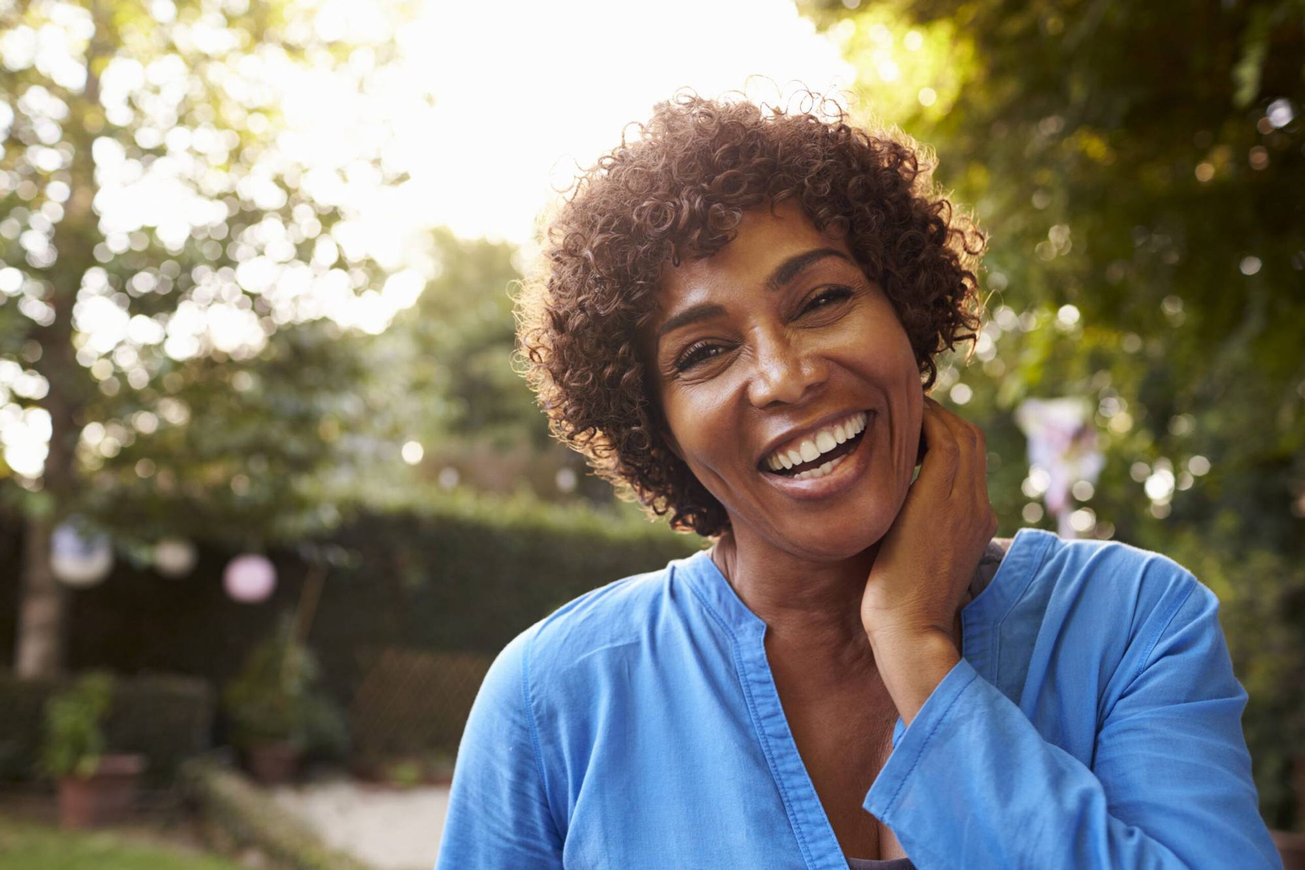 Woman smiling, holding her neck