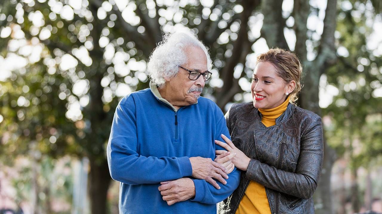 A father and his adult daughter walking together outside, caregiver, Next Avenue, helping an aging parent