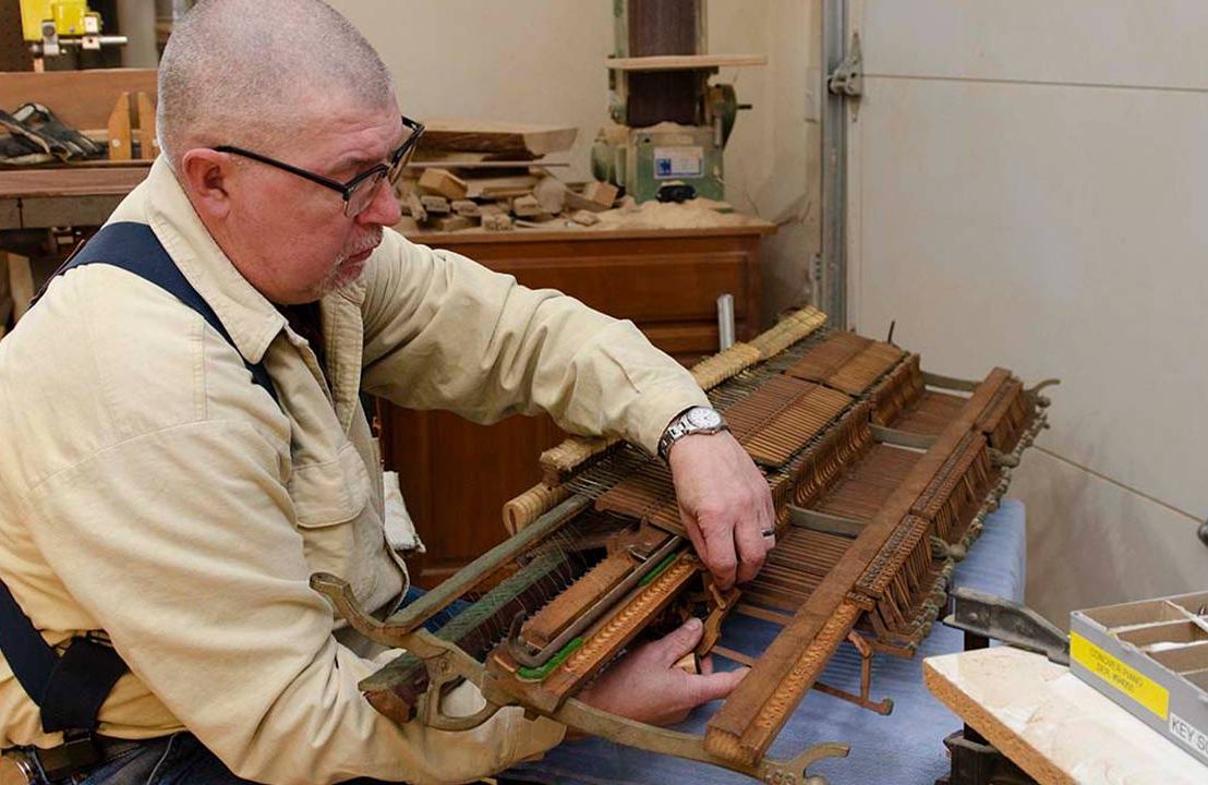 Man at workbench fixing a discarded piano, pianos, restoration, Next Avenue