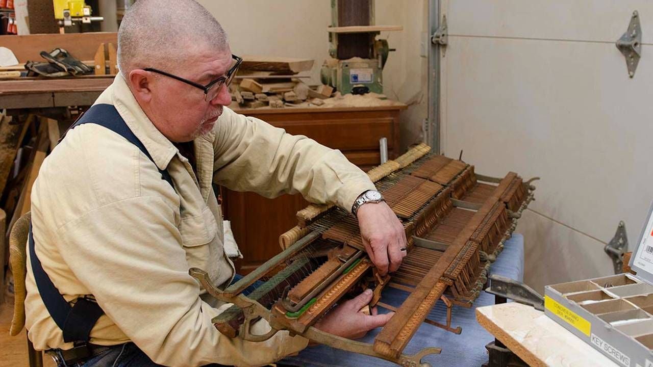 Man at workbench fixing a discarded piano, pianos, restoration, Next Avenue