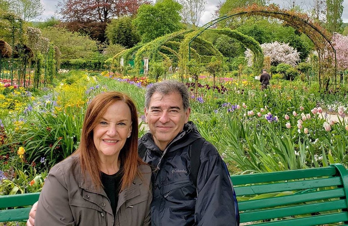Couple sitting on a bench outside in a spring garden, bucket list, travel, Next Avenue