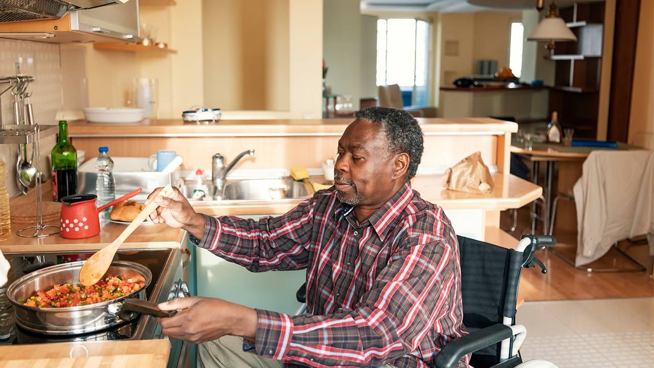 Older man in wheelchair cooking dinner, caregivers, family, COVID-19, Next Avenue