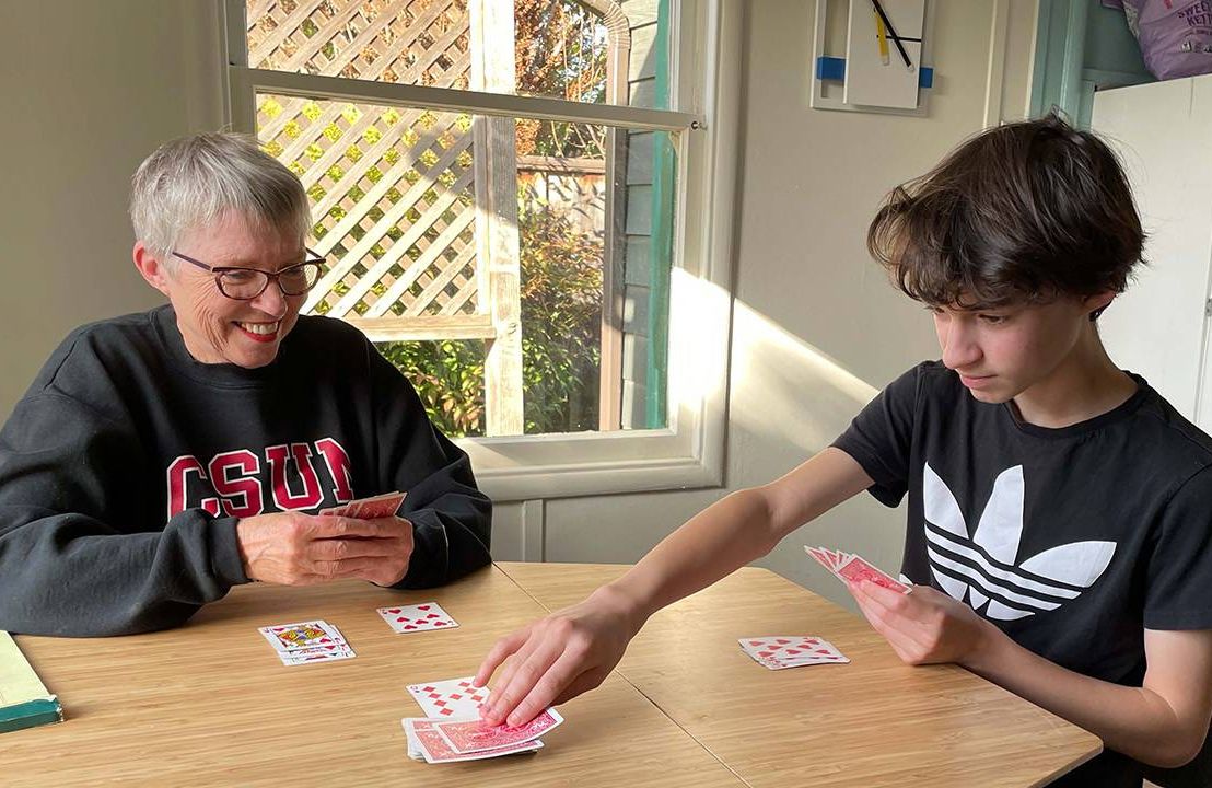 Grandparents and grandson playing cards at the dining table, multigenerational living, Next Avenue