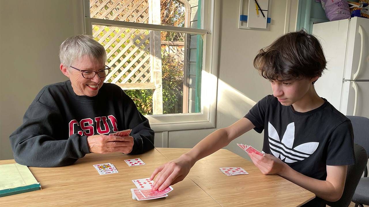 Grandparents and grandson playing cards at the dining table, multigenerational living, Next Avenue