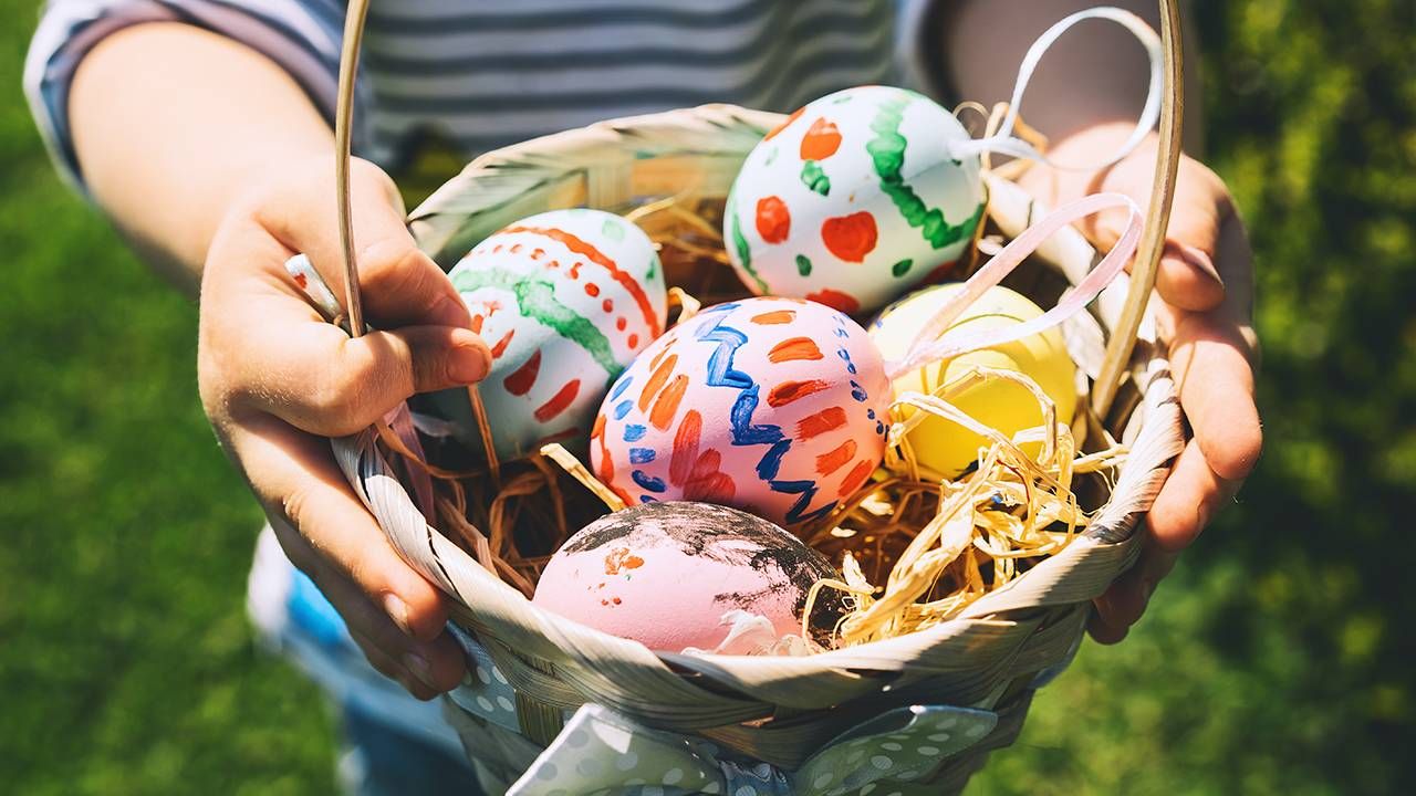 Close up of a child holding an easter basket with colorful painted eggs, Easter eggs, hunt, Next Avenue