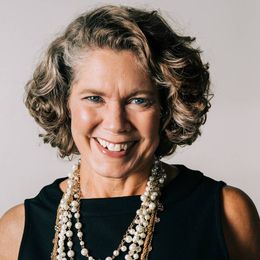 carrie mcconkey smiling at the camera wearing a black shirt and necklaces.