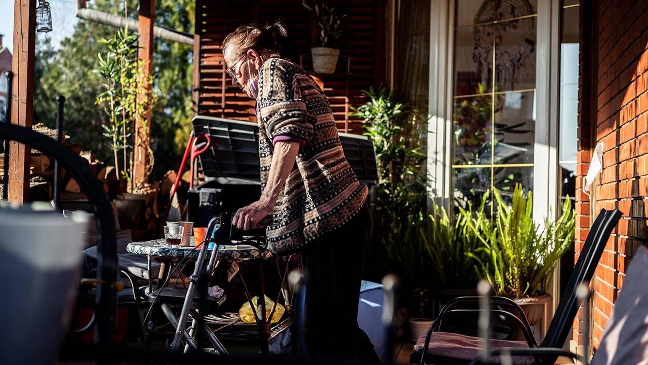 Older woman walking with walker wearing facemask on porch, ageism, ableism, Next Avenue