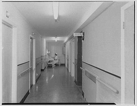 hallway interior with nurse sitting at desk, history, Next Avenue, history of nusring homes