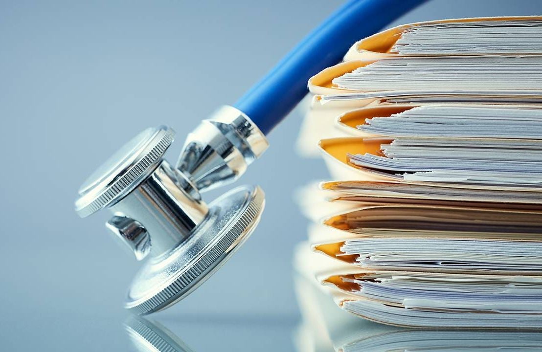 a stethoscope on top of a pile of medical records, health, Next Avenue