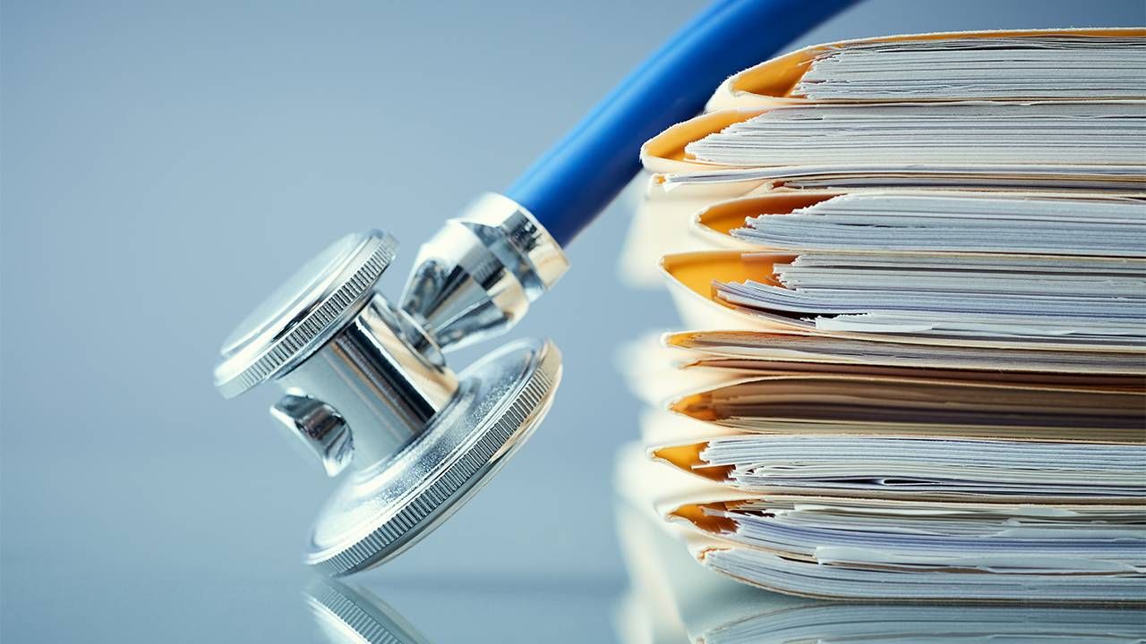 a stethoscope on top of a pile of medical records, health, Next Avenue