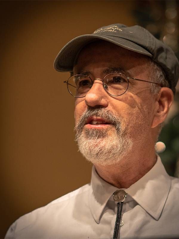 Close up shot of middle aged man wearing baseball hat and bolo tie. Poets, poetry, Next Avenue