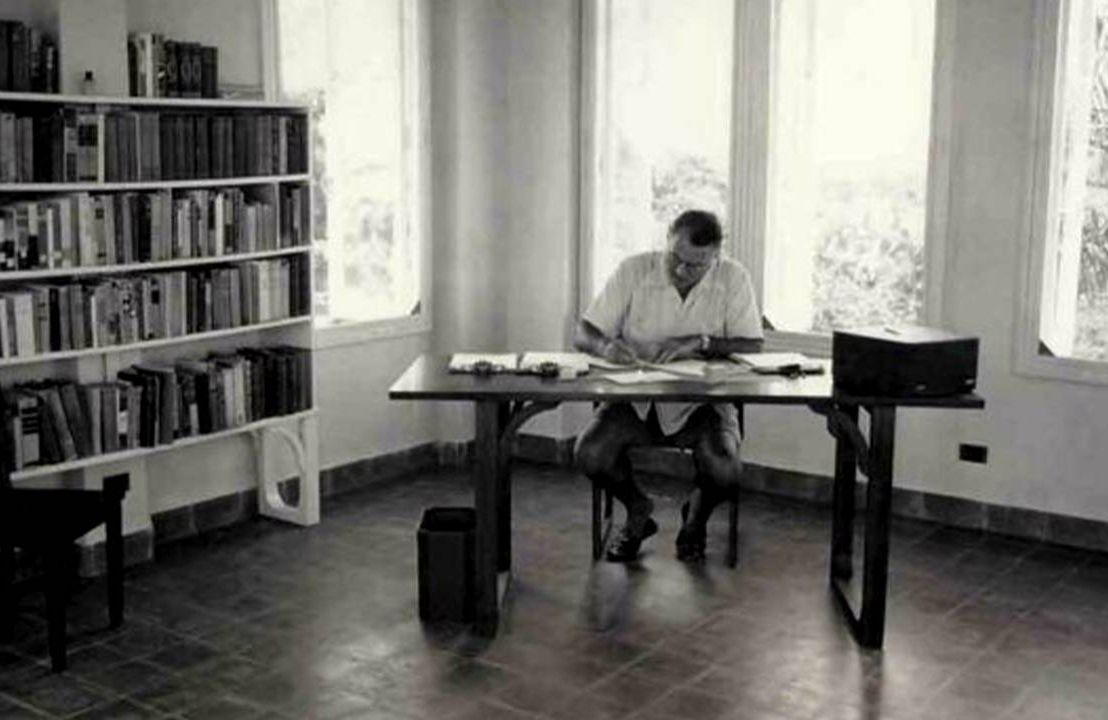 Old photo of Hemingway sitting at his desk, Next Avenue
