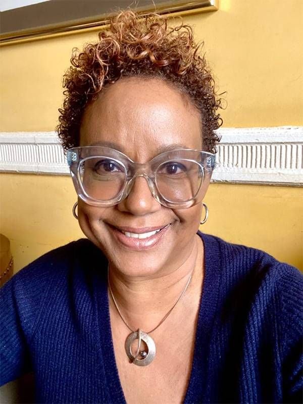 A woman with short curly hair and clear glasses smiling. Nonprofits, Next Avenue