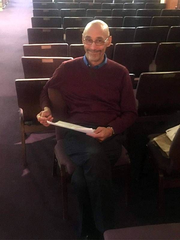 An older man sitting alone in a theater smiling. Drama, Actors, Next Avenue