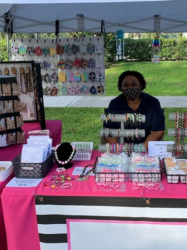 Woman sitting a the table of a handmade jewelry booth at yard sale