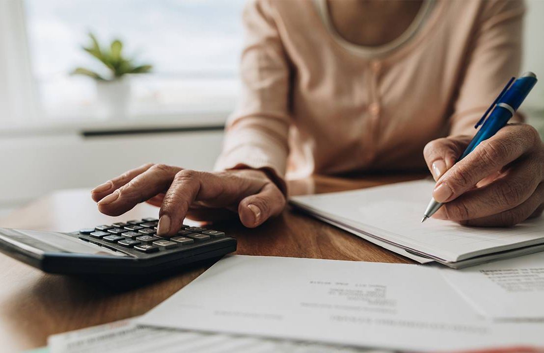 A close up of a woman's hands calculating retirement savings.