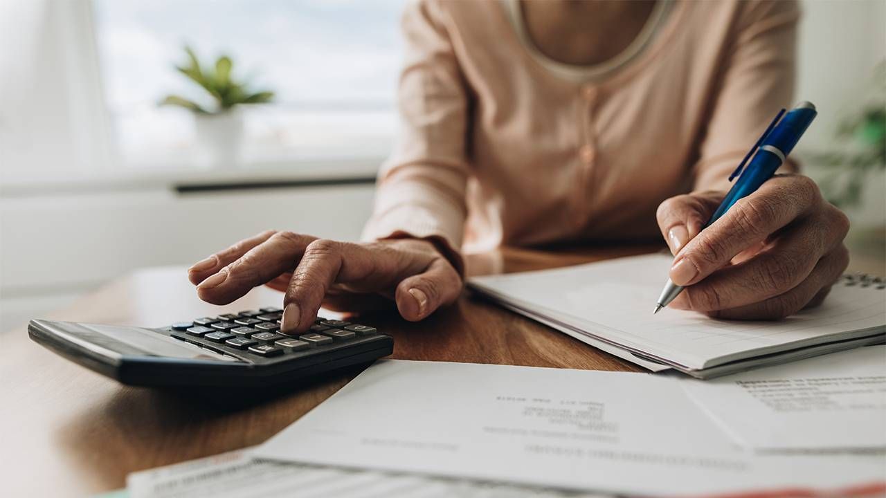 A close up of a woman's hands calculating retirement savings.