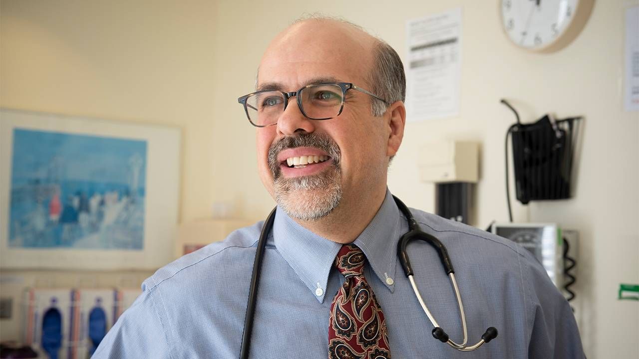 Photo of poet Dr. Campo wearing a stethoscope around his neck in his office. Poets, poetry, Next Avenue