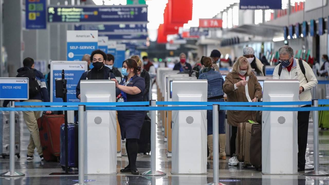 People standing at a ticketing kiosk in an airport wearing face masks. Travel, vaccinated travel, Next Avenue