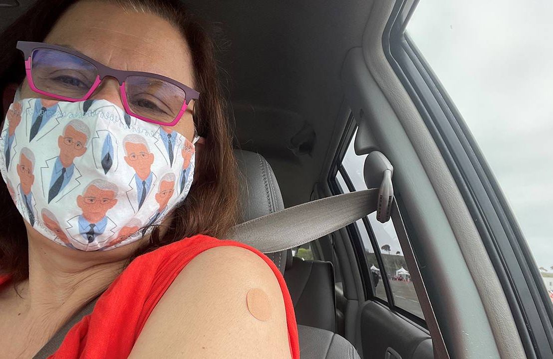 A woman wearing a face mask in her car displays her vaccine bandaid. Which vaccine to get, COVID-19 vaccine, Next Avenue