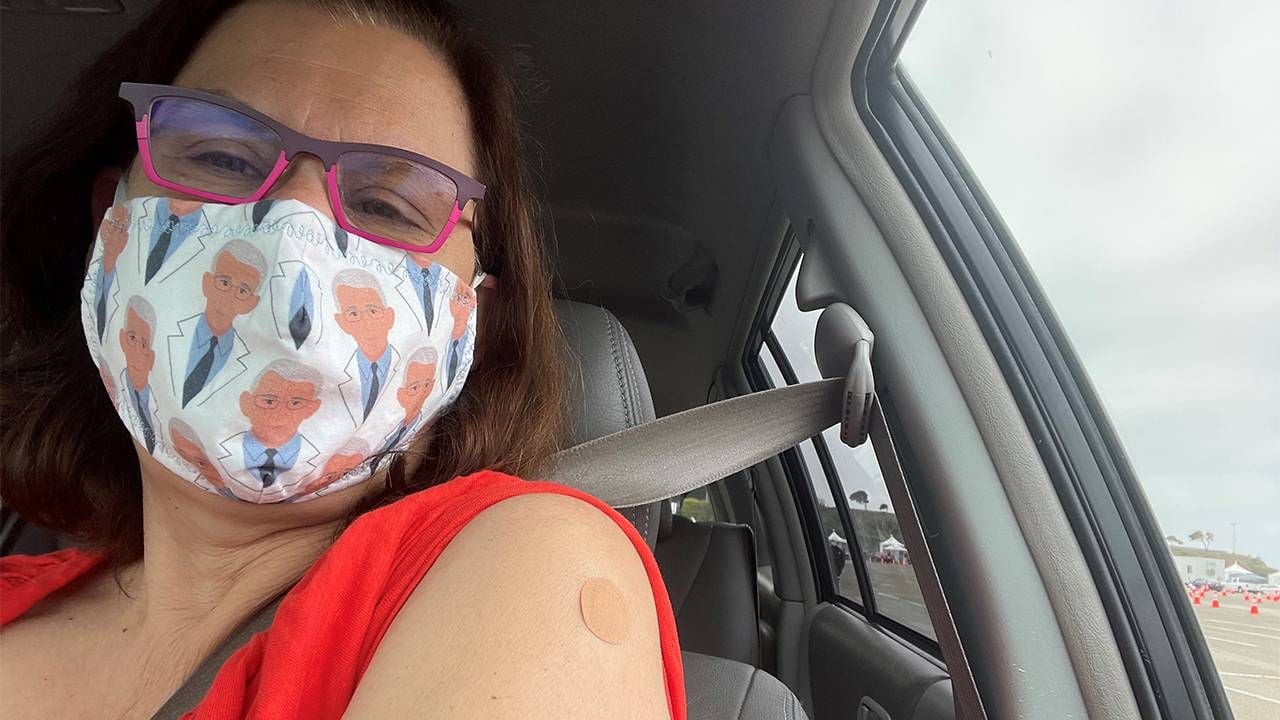 A woman wearing a face mask in her car displays her vaccine bandaid. Which vaccine to get, COVID-19 vaccine, Next Avenue