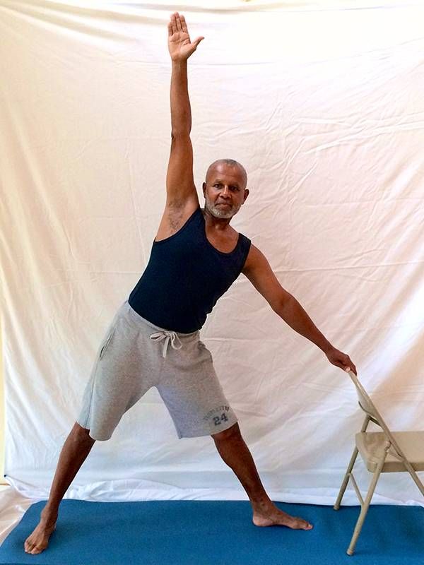 Man standing in triangle pose, yoga, Next Avenue