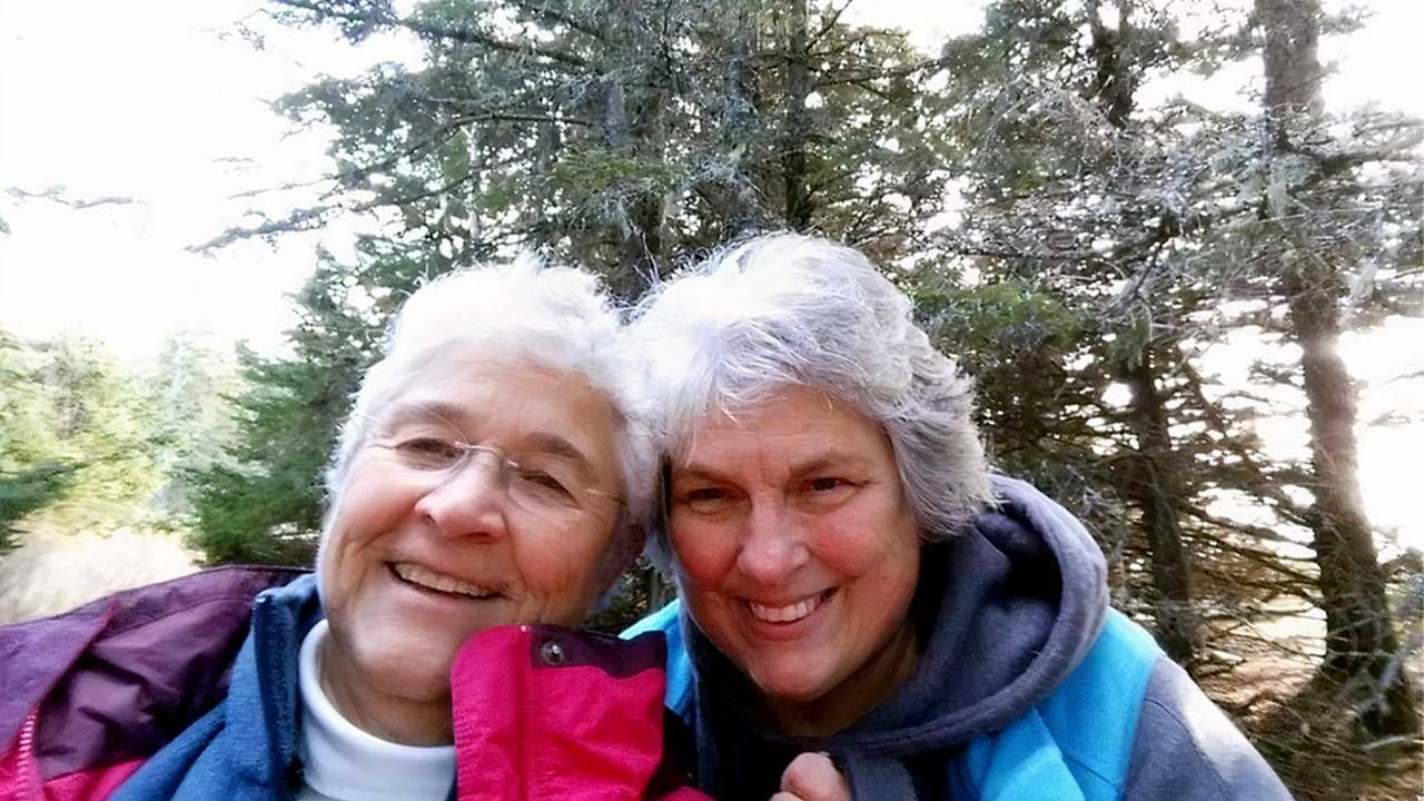 A couple smiling with pine trees behind them. LGBTQ senior housing communities, LGBTQ seniors, Next Avenue