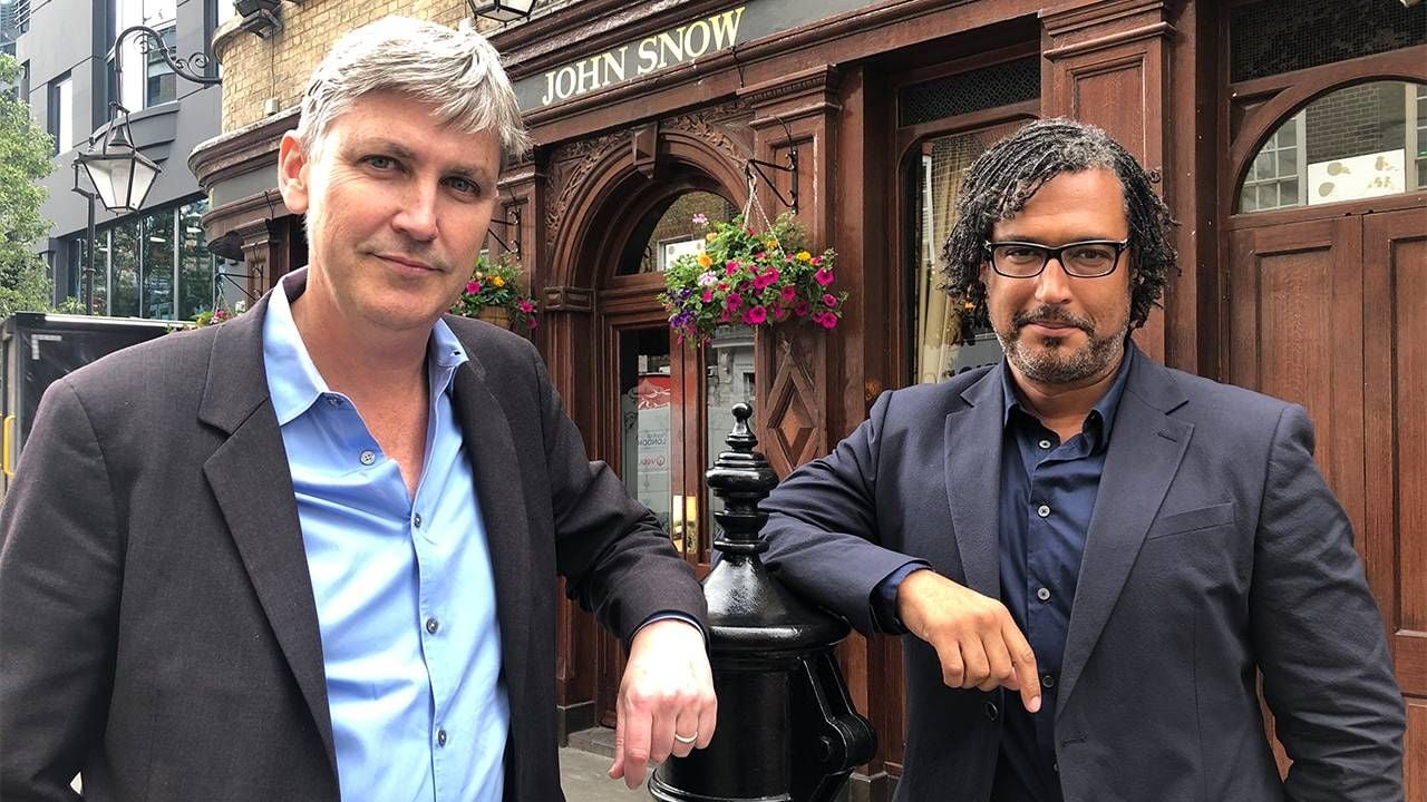 Two men standing outside on the street in front of a "John Snow" sign. Extra life, PBS, Next Avenue