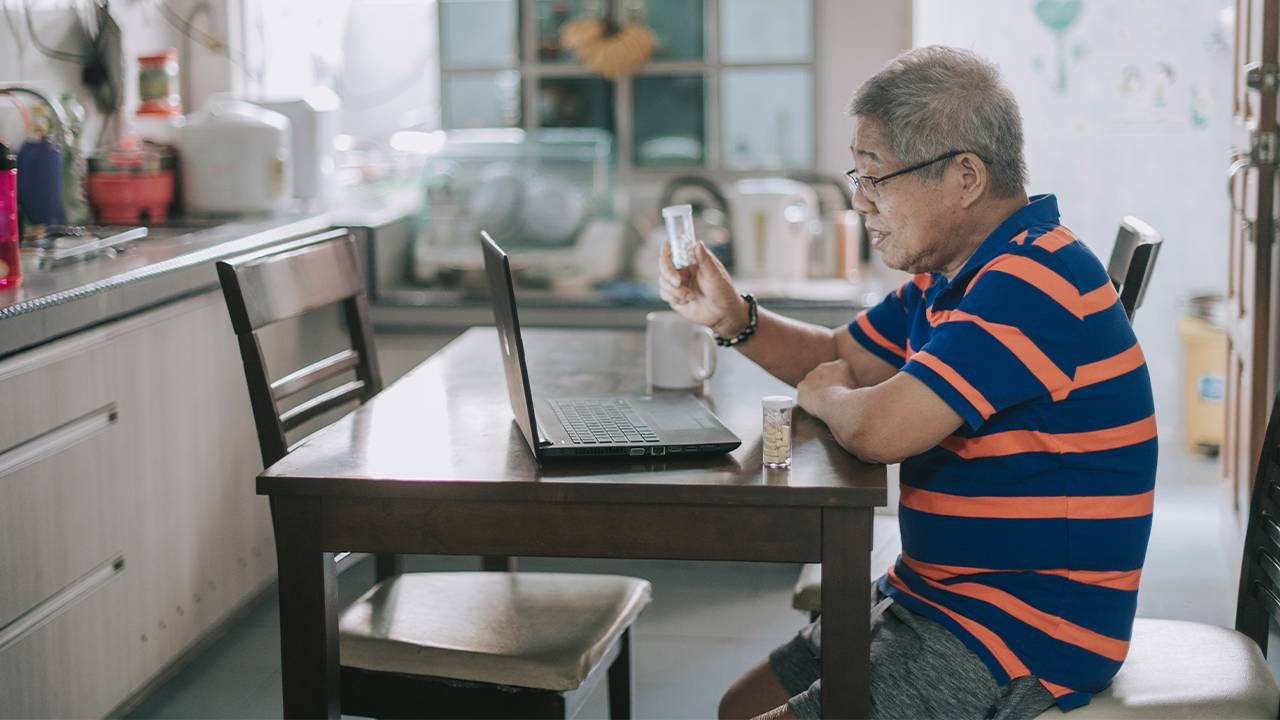 A midle aged man sitting at table on a telehealth doctor appointment. Ask the doctor, health, Next Avenue