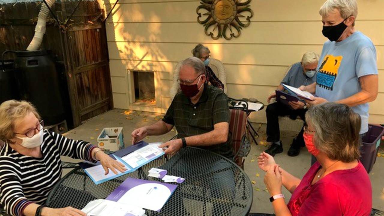 A group of volunteers outside putting together folders of information. Community, dementia, Next Avenue