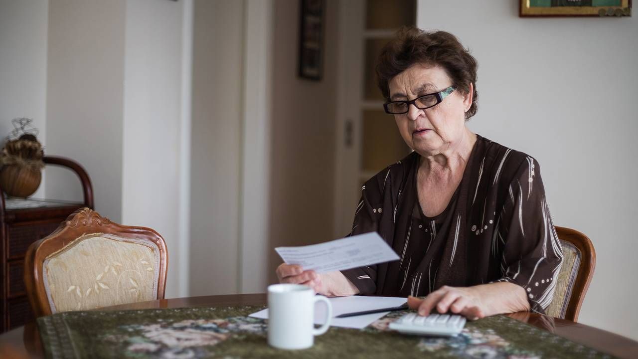 An older woman looking over her bills and using a calculator. Low income adults, moderate income, Next Avenue