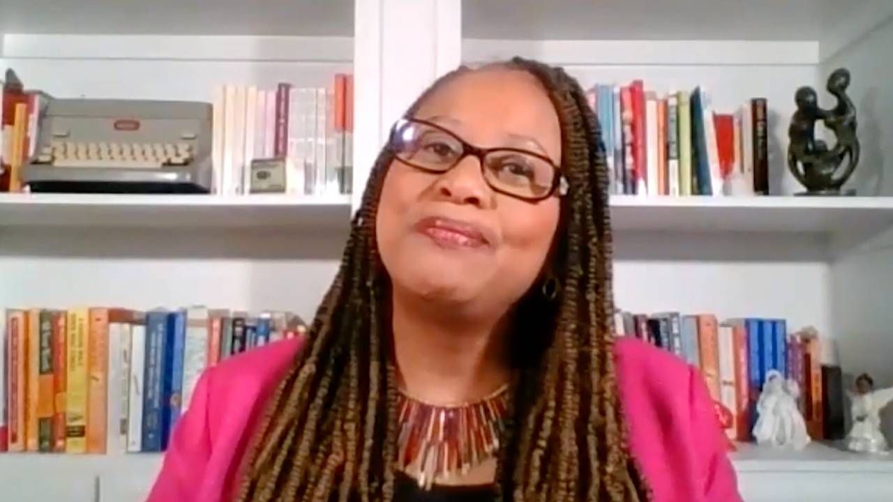 Michelle Singletary wearing a pink blazer in front of a bookshelf. Money, finances, Singletary's, Next Avenue