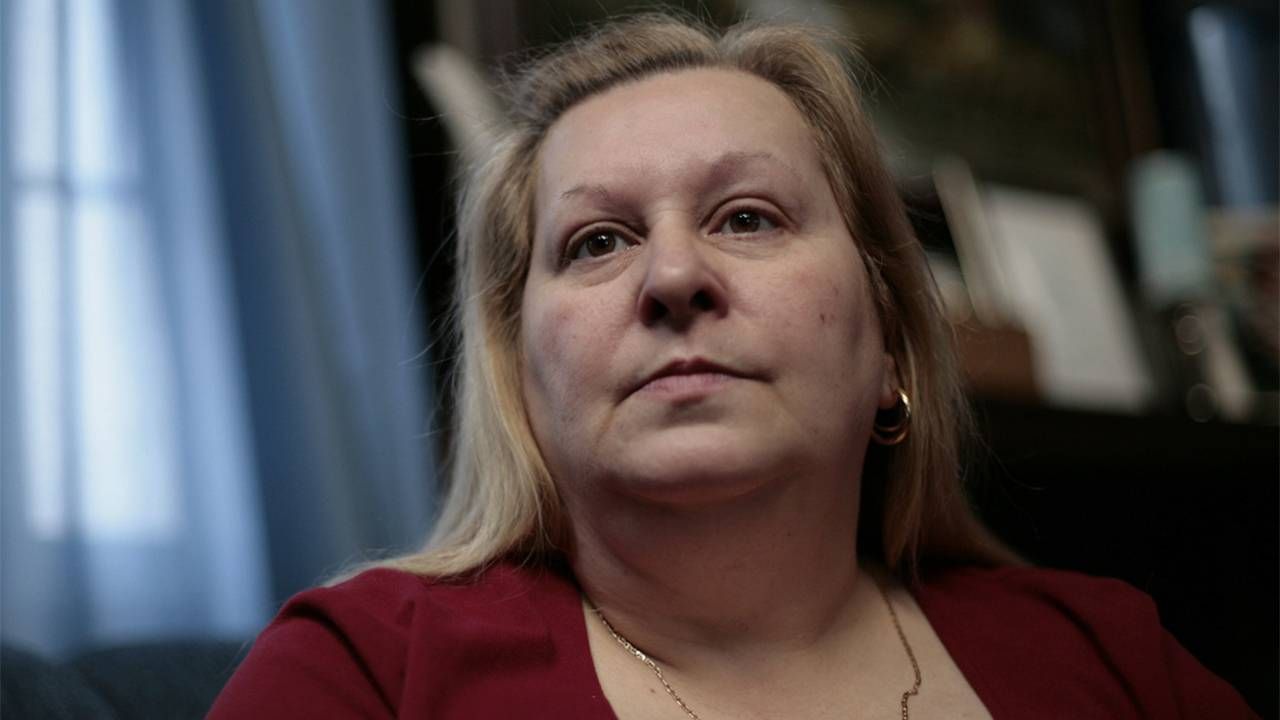 A closeup of a woman with blonde hair wearing a red shirt and gold earrings. Older workers, minimum wage,Next Avenue