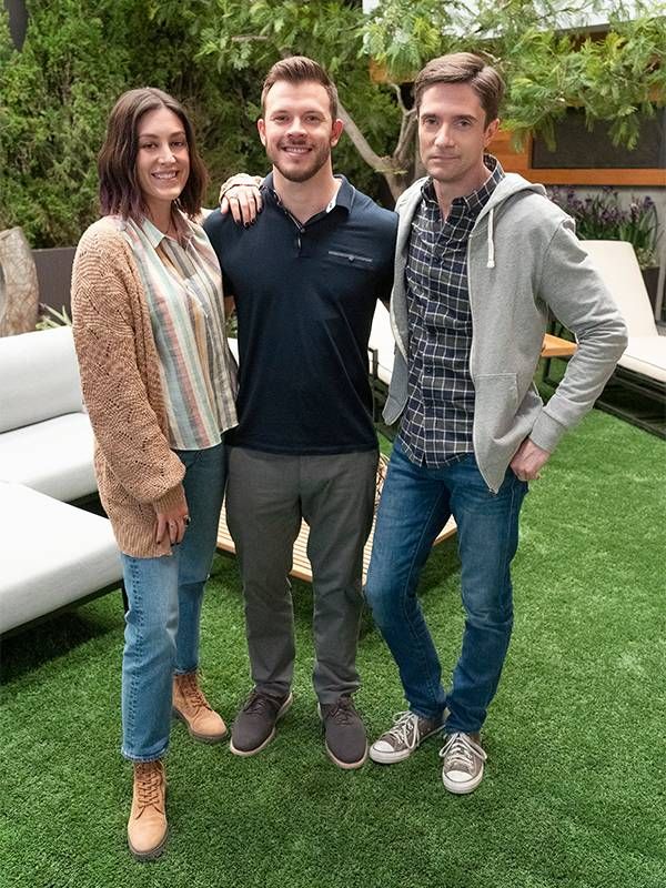 Three siblings standing arm in arm, smiling.