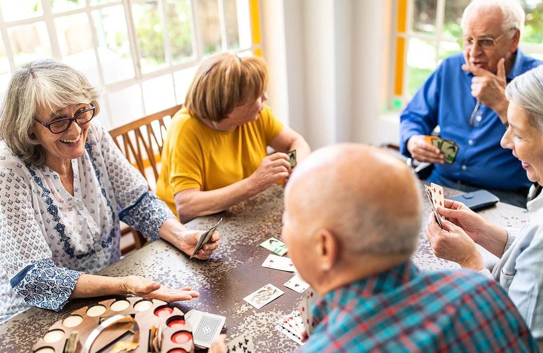 a group of older adults sit around a table talking