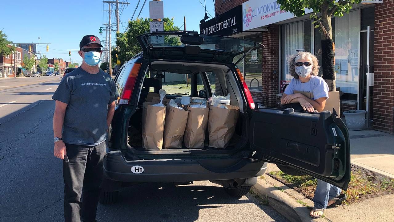 Two older adults standing in front of a car filled with groceries. Next Avenue, Villages Neighborhood Network