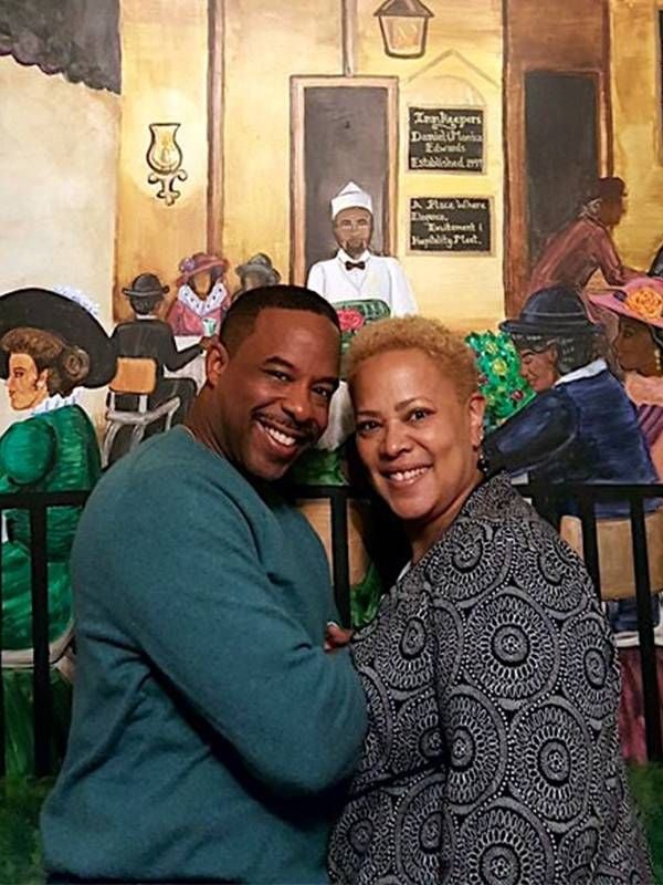 A couple smiling in front of a mural. Next Avenue, Black and Latina women, COVID-19 pandemic