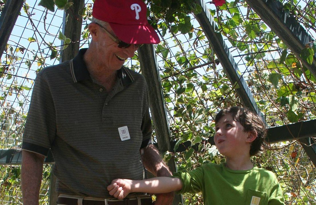 A grandfather and his grandson smiling in a garden. Dad, books, Next Avenue