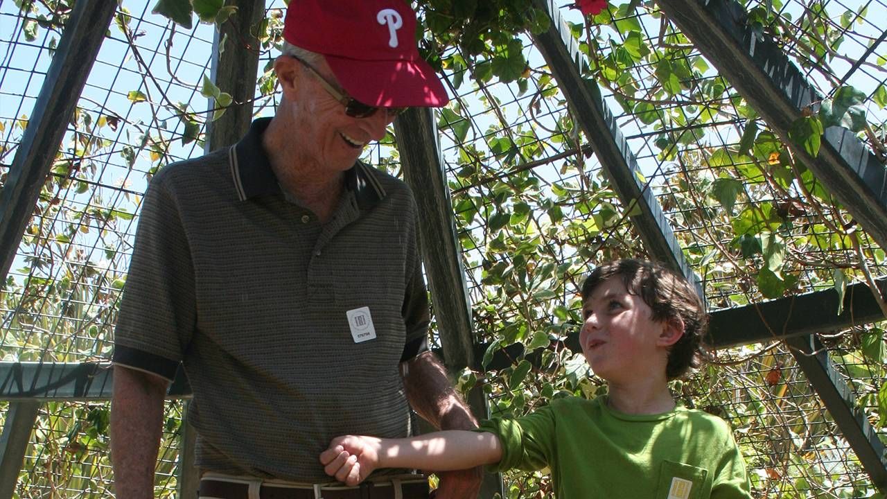 A grandfather and his grandson smiling in a garden. Dad, books, Next Avenue