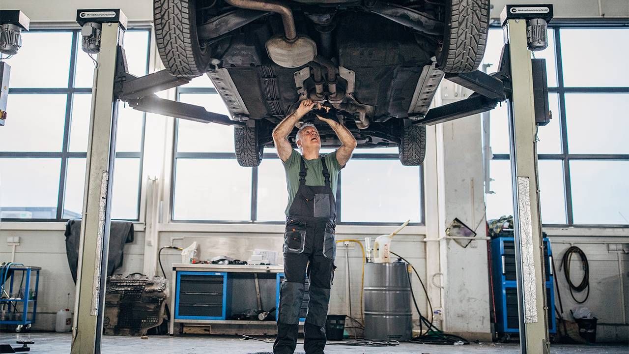 A mechanic fixing a car in the auto shop. Next Avenue, car insurance