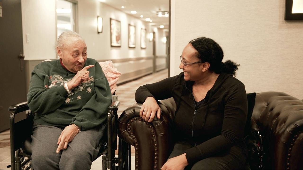 A caregiver sitting next to her mother who is in a wheelchair. Next Avenue, It's not a burden, caregiving