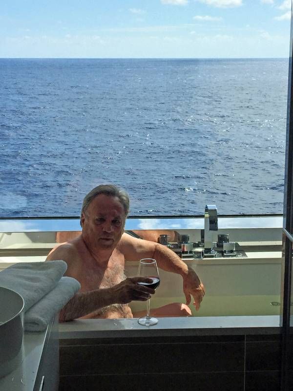 A man sitting in a bathtub holding a glass of wine. Cruise, trip, travel, Next Avenue