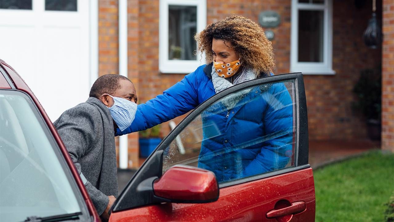 An adult daughter helping her older father into the car. Guardianship, Next Avenue, eldercaring coordination