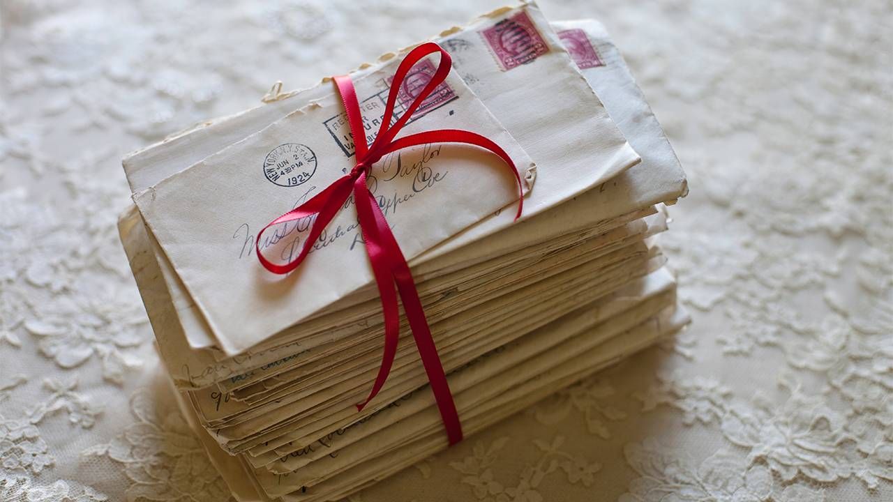 A stack of old letters with a red ribbon. Love, Next Avenue, letters