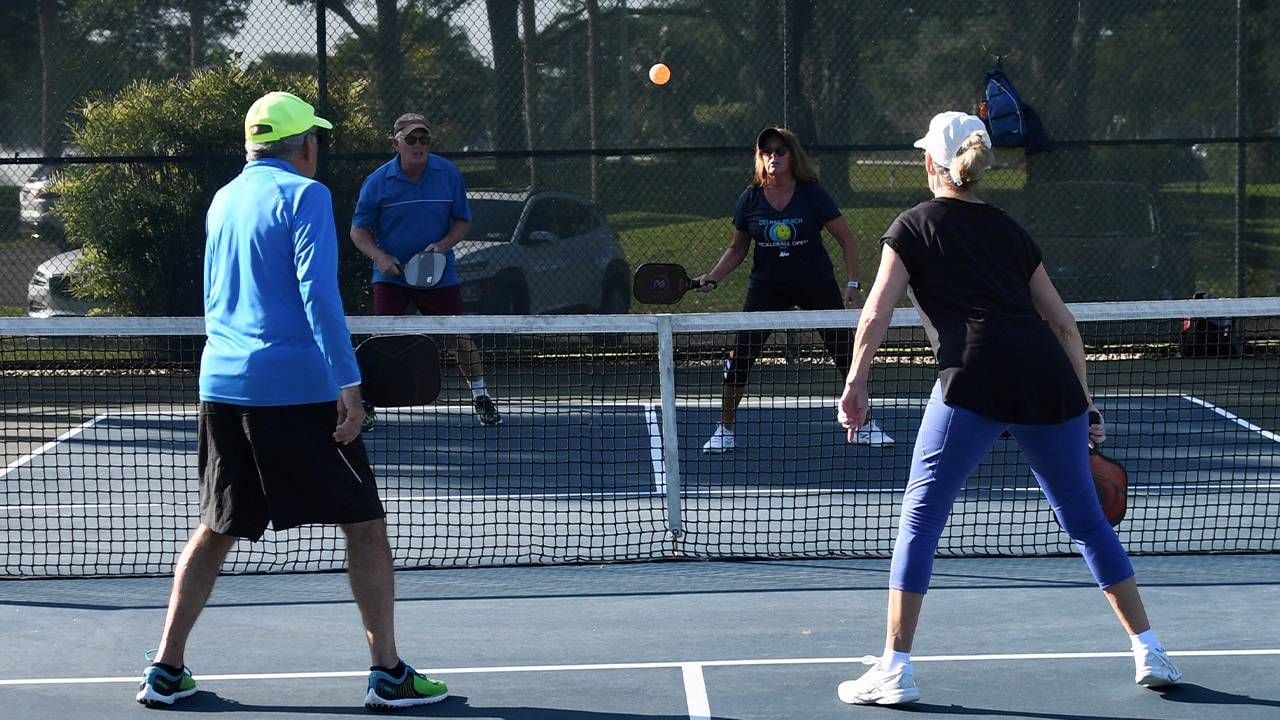 A group of people playing pickleball outside. Next Avenue