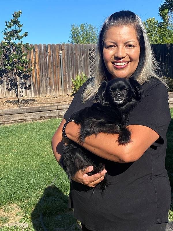 A woman holding a little black dog in her backyard. Next Avenue, Black and Latina women, COVID-19 pandemic