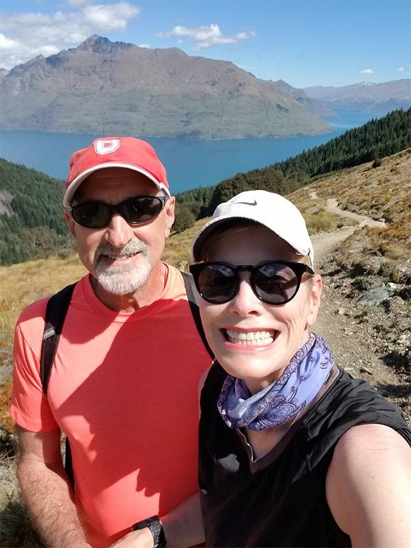 A couple hiking in New Zealand with mountains and a lake behind them. Traveling, senior nomads, travel, Next Avenue