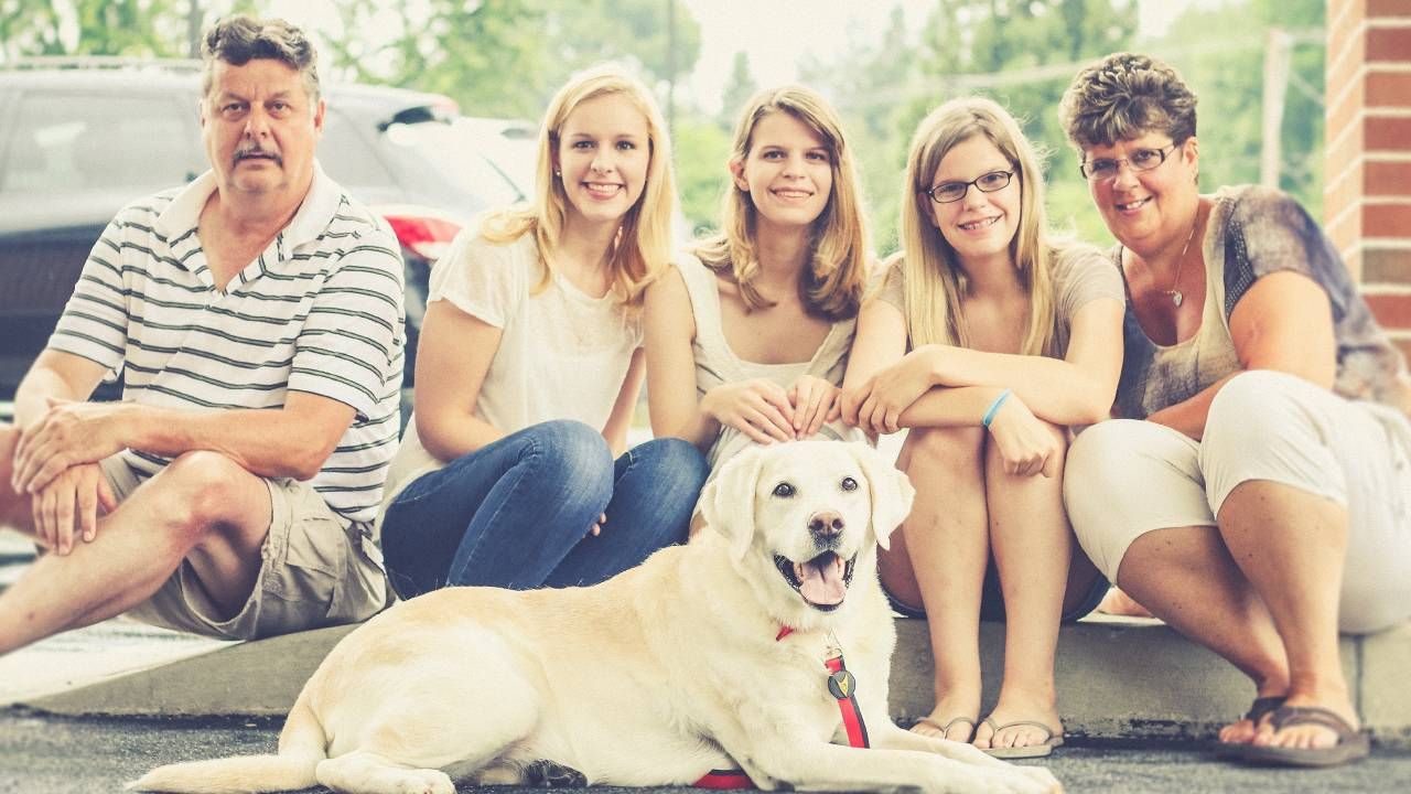 A family and their dog sitting on a curb. COVID-19, survivor's guilt, Next Avenue